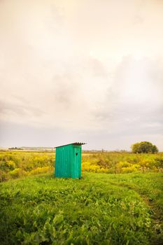 wooden toilet with a carved window in the shape of a heart, an open field.