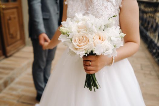 The bride holds a wedding bouquet of roses in her hands. Wedding floristry.