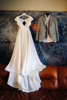 the bride's wedding dress and the groom's suit hanging on the wall.
