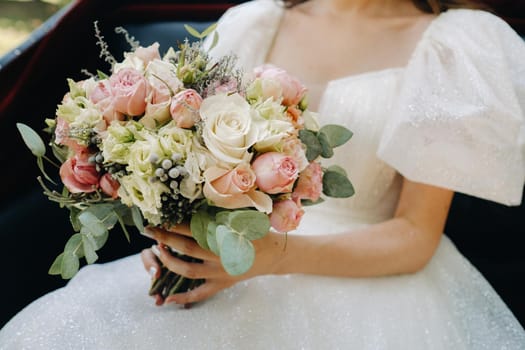 The bride holds a wedding bouquet of roses in her hands. Wedding floristry.