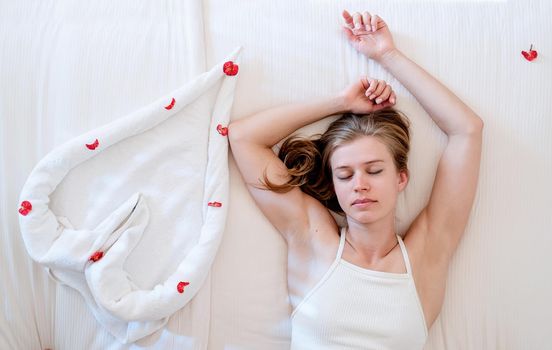 Love, valentines day and emotion. Woman lying on the bed with heart shped towels showing heart gesture