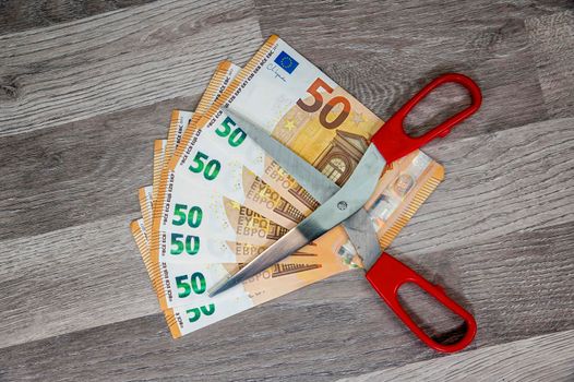 50 euro banknotes with kitchen scissors on top