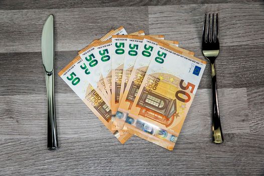 50 euro banknotes with fork and fork on wooden surface