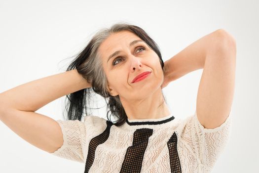 Studio photo of middle aged woman starting getting grey-haired wearing black and white clothes on white background, middle age sexy lady, happy life concept.