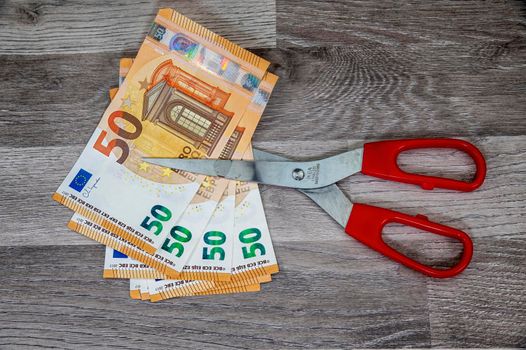 cut 50 banknotes with euro scissors on wooden table