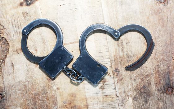 Escape concept. Old metal unfastened handcuffs on wooden background