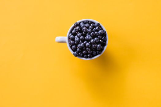 Art Nouveau style concept image, White cup full of blueberries on a colored geometric trendy background, food and healthy concept