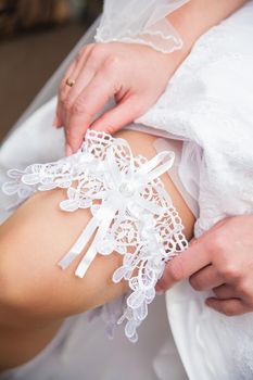 The bride holds the white lace garter in the studio