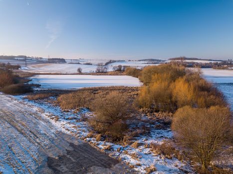 Aerial bird view of beautiful winter landscape with frozen pond covered with snow. Central european countryside. Czech Republic, Vysocina Highland region, Europe