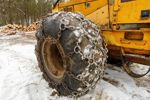 Close up of Winter Chains on Yellow Logging Skidder for extra grip in the snow . High quality photo