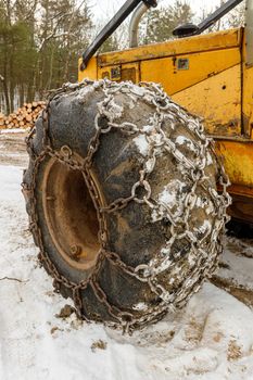 Close up of Winter Chains on Yellow Logging Skidder for extra grip in the snow . High quality photo