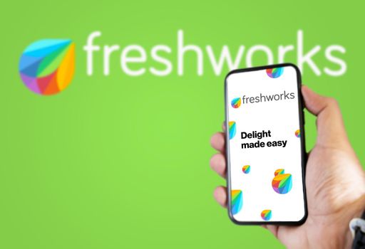 San Francisco, USA, December 2021: Hand holding a phone with Freshworks mobile application on the screen. Freshworks logo blurred on a green background. Software as a service platform company