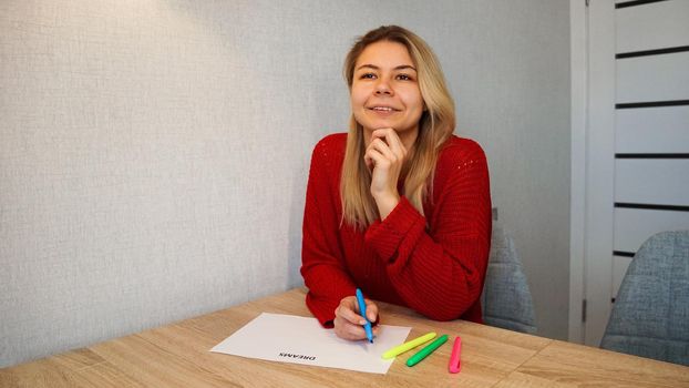 Portrait of young beautiful thoughtful lady writing down her dreams list. Visualization of dreams