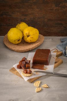 Marmalade in crackers on a kitchen counter with quinces on a cork tray.