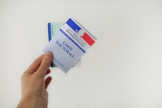 PARIS, FRANCE - MARCH 09, 2020: A Hand holds a french electoral card and an identification card for voting