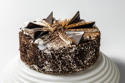 cake with chocolate, sprinkled with chocolate chips, on a tray on a white background.