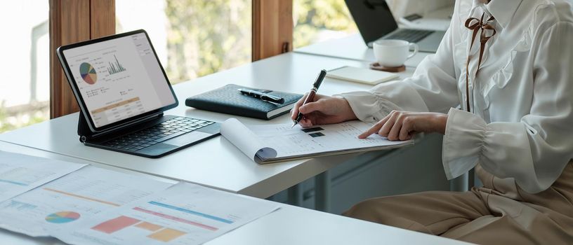 Close up a accountant working about financial with digital tablet and paperwork at office to calculate expenses, Accounting concept