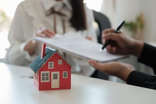 Real estate brokers point to a contract paper and advise customers to sign their names. customer sign agreement contract signature for buy or sell house. Real estate concept contact agreement concept.