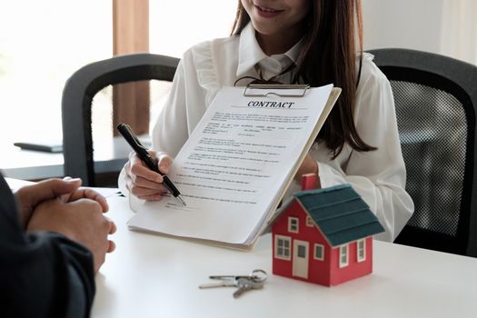 Real estate brokers point to a contract paper and advise customers to sign their names. customer sign agreement contract signature for buy or sell house. Real estate concept contact agreement concept.