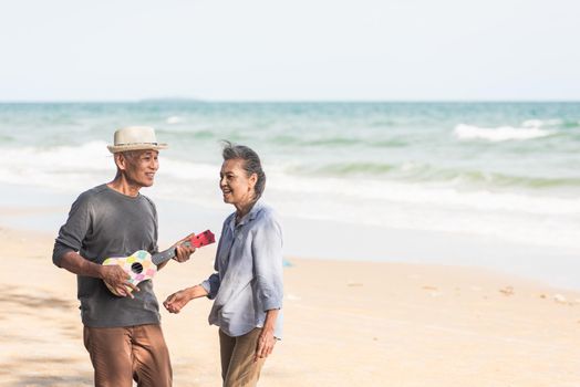 Happy senior couple relaxing outdoors singing and playing acoustic guitar at beach near sea sunny day, Mature man playing ukulele for his wife at sea, plan life insurance at retirement couple concept