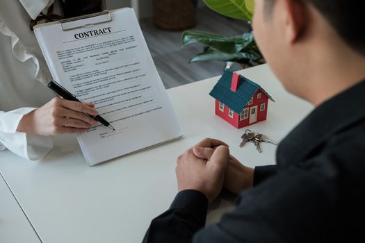 Real estate brokers point to a contract paper and advise customers to sign their names. customer sign agreement contract signature for buy or sell house. Real estate concept contact agreement concept.