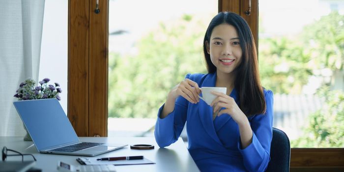 Asian Woman blogger wear blue suit talking with followers, live streaming on social media application. Freelance work from home concept