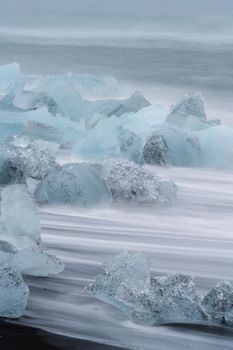 Long exposure of icebergs over Jokulsarlon black diamong beach, vertical composition
