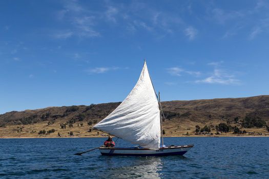 Titicaca Lake, Peru - October 14, 2015: A man steering a sailboat on the Tititaca Lake on the peruvian side.