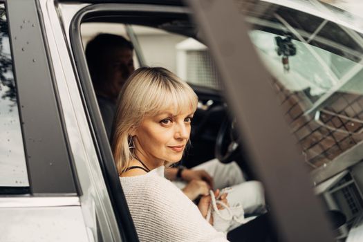 An adult mature happy romantic couple in love outdoors in car. A blonde caucasian man and woman spend time together. Senior wife and husband sit in the car to go for a walk