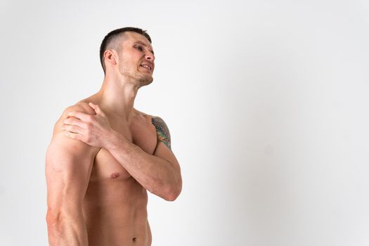 A sore shoulder joint muscle in a white man on a white background back body injury, male young human holding. lumbar sickness, back suffer attractive