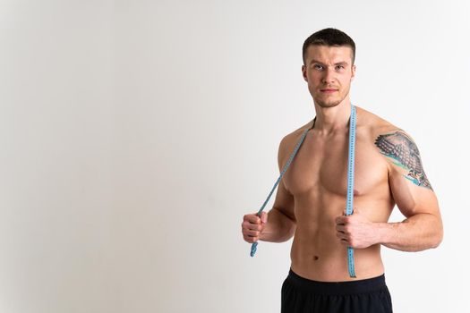 A man measures the waist of a metre and poses against a white background isolated body diet hand, slim sexy woman bodybuilder Weight studio, one sport attractive tape