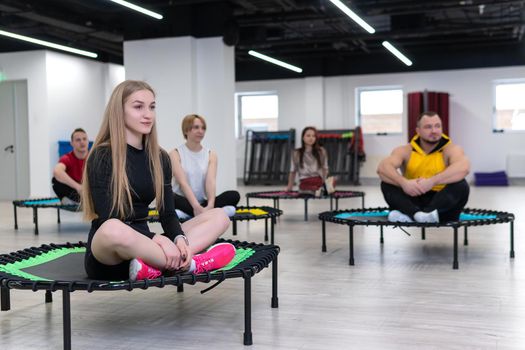 Women's and men's group on a sports trampoline, fitness training, healthy life - a concept trampoline group batut girl healthy, In the afternoon female team for gym for sport motion, smiling happiness. Legs beauty indoor, coach