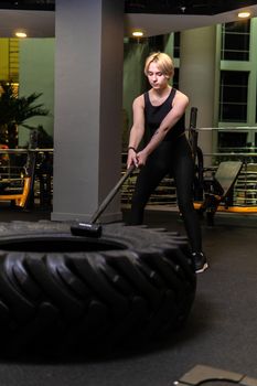 Wheel with sledgehammer girl stands tire gym fit, for equipment strong from athletic athlete lifestyle, activity leaning. Braids muscles black, female