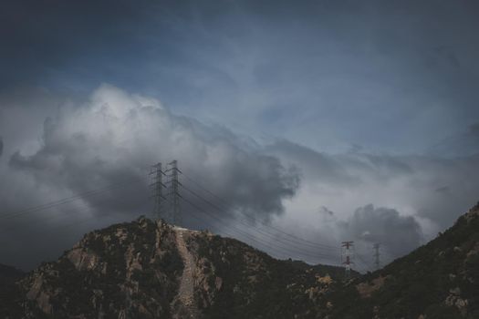 Real nature landscape background. Rocky mountain, cloudy Pale Blue dark stormy sky autumn day, high voltage Electricity power pylons. Cold mood feelings. Problem Difficult obstacles, discomfort.