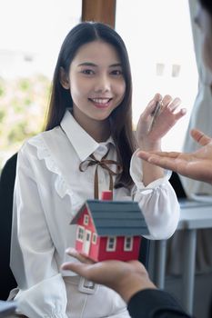 Close up of Business woman giving house key after signing agreement for buying house. Bank manager and real estate concept