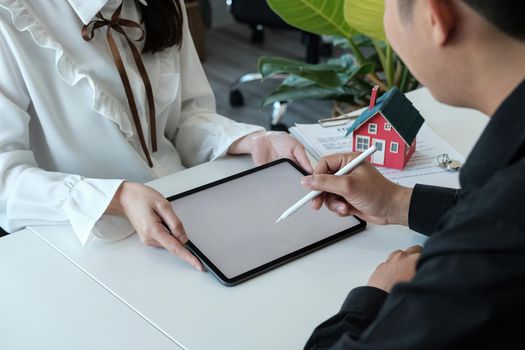 Real estate brokers point to a contract and advise customers to sign name digital tablet. customer sign agreement contract signature for buy or sell house. Real estate concept contact agreement concept.