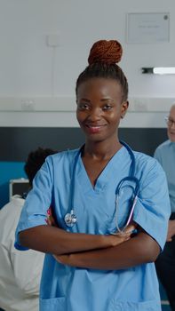 Portrait of woman working as nurse wearing uniform looking at camera in hospital room cabinet. Young adult healthcare assistant with stethoscope smiling at medical clinic in doctors office