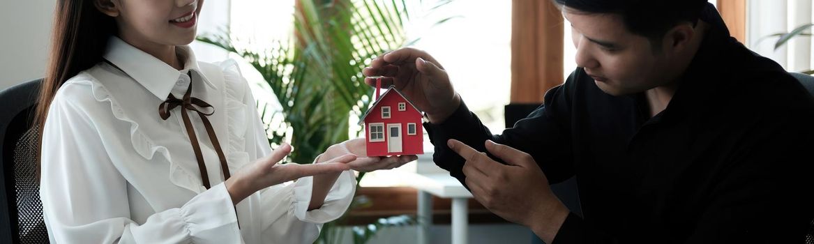 Asian couple are using their hands to protect The concept of the use of gestures in real estate investors, leasing insurance, purchase and sales contracts and maintenance.