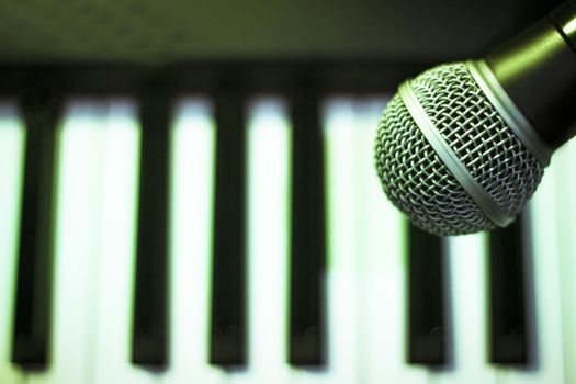 Microphone over piano keys in dim light. No people