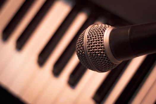 Microphone over piano keys in dim light. No people