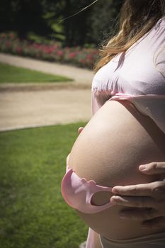 Seven months pregnant woman with baby mask over her gut. Pink color