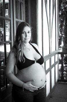 Seven months pregnant young woman dressed in black bikini and jeans