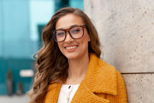 Business woman dressed yellow coat standing outdoors corporative building background Caucasian female business person eyeglasses on city street near office building with windows Stylish businesswoman