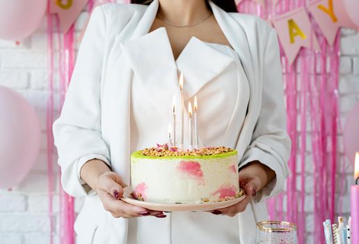 Birthday party. Birthday tables. Attractive woman in white party clothes preparing birthday table with cakes, cakepops, macarons and other sweets