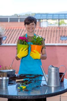 Portrait of a smiling teen holding plants on the terrace.