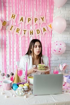 Birthday party. Birthday tables. Attractive brunette woman in white party clothes celebrating birthday using video call chatting with friends
