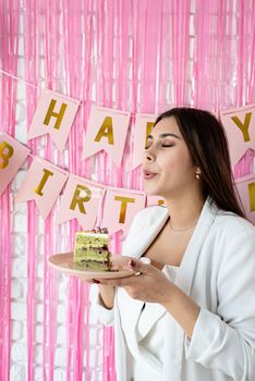 Birthday party. Birthday tables. Attractive brunette woman in white party clothes preparing birthday table with cakes, cakepops, macarons and other sweets, making wish