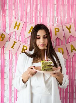 Birthday party. Birthday tables. Attractive brunette woman in white party clothes preparing birthday table with cakes, cakepops, macarons and other sweets, making wish