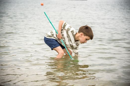 One little boy alone exploring the beach at low tide walking towards the sea coast. happy childhood concept.