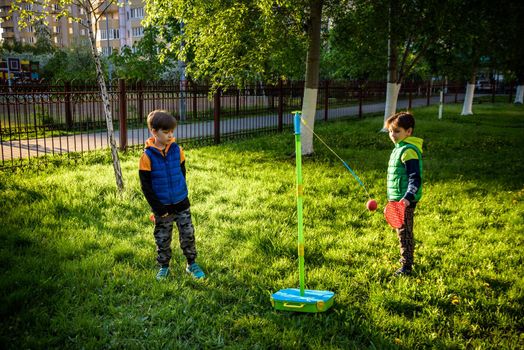 Two friends are playing tetherball swing ball game in summer camping. Two boy brother happy leisure healthy active time outdoors concept.